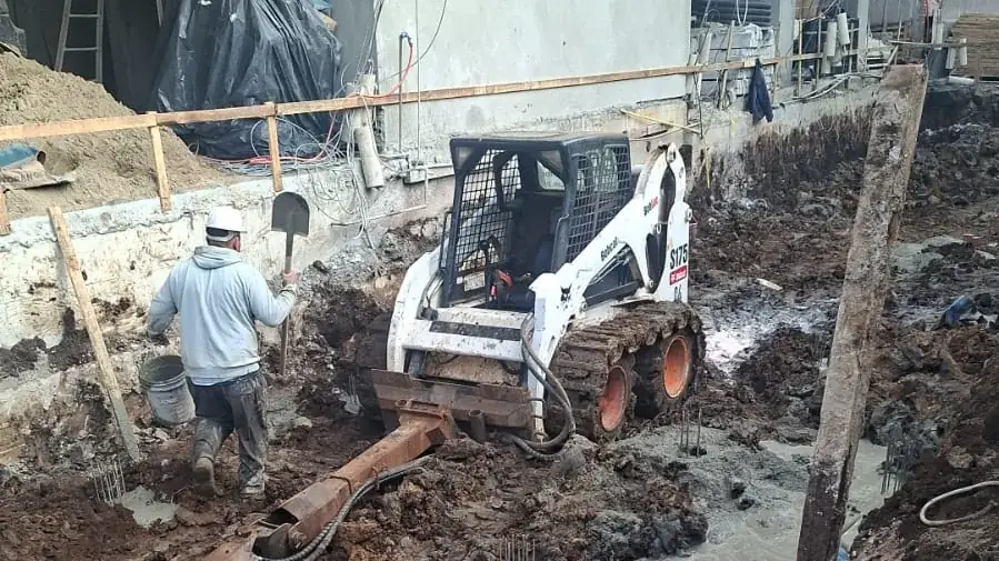 Mini carregadeira Bobcat com perfuratriz (trado) em obra em Curitiba